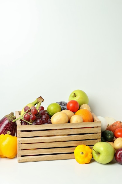 Scatola di legno con diverse verdure e frutta sul tavolo bianco