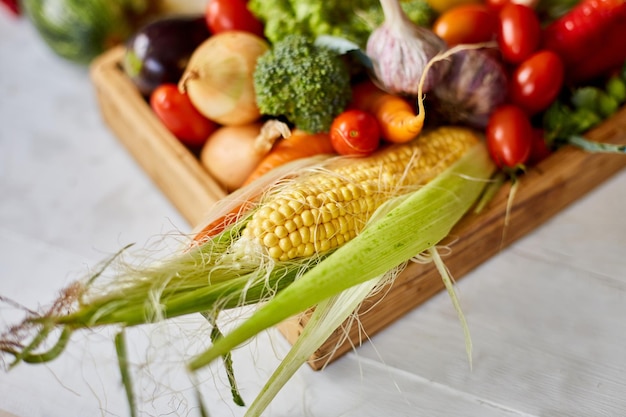 Scatola di legno con diverse verdure fresche di fattoria su sfondo bianco