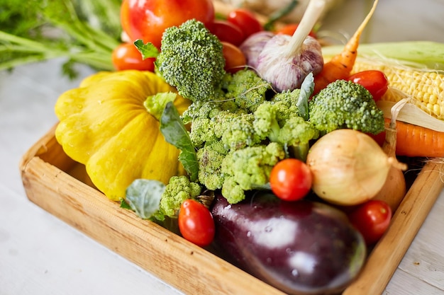 Scatola di legno con diverse verdure fresche di fattoria su sfondo bianco