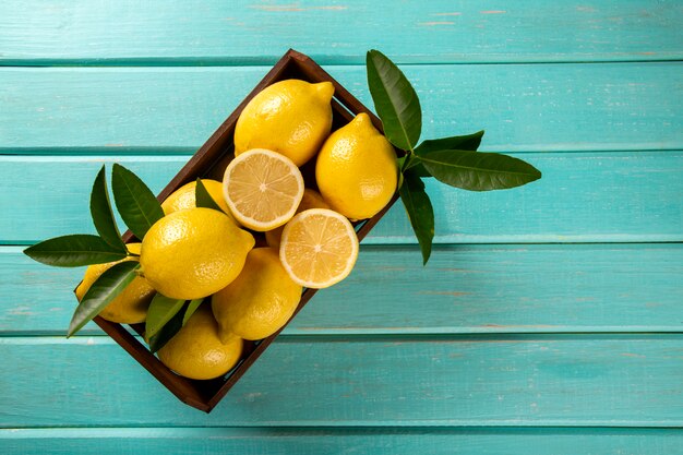 Scatola di legno con limoni su fondo di legno verde