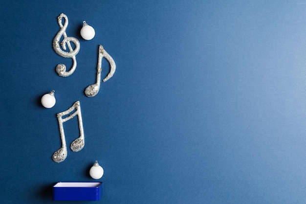 Scatola di metallo con palle di Natale sparse e note musicali su sfondo blu