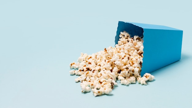 Scatola di popcorn versato su sfondo blu