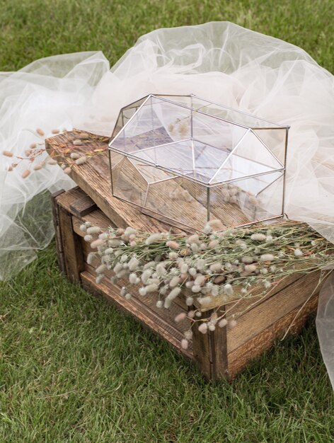 Scatola di vetro per buste per biglietti di auguri su tavolino in legno e tessuto bianco con piante come decorazione