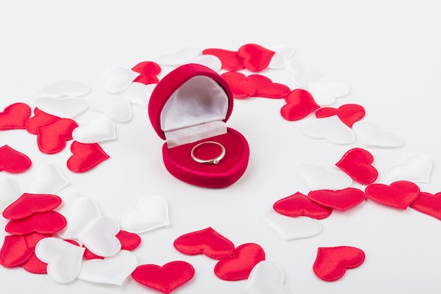 Scatola per anello a forma di cuore in velluto rosso con anello di fidanzamento all'interno tra cuori rossi e bianchi in tessuto. Regalo per San Valentino, compleanno. Concetto di proposta di matrimonio. Avvicinamento