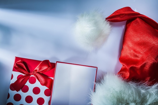 Scatola regalo avvolta con cappuccio di Babbo Natale su sfondo bianco