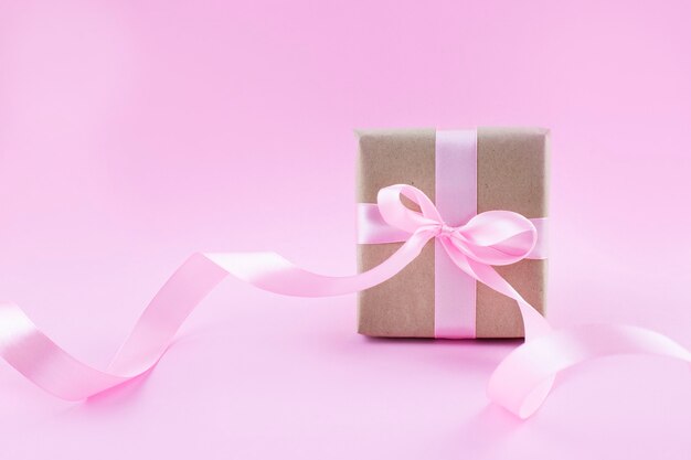 Scatola regalo avvolta in carta artigianale con nastro rosa