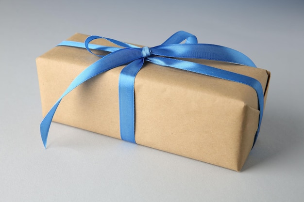 Scatola regalo con arco di satin blu su sfondo chiaro