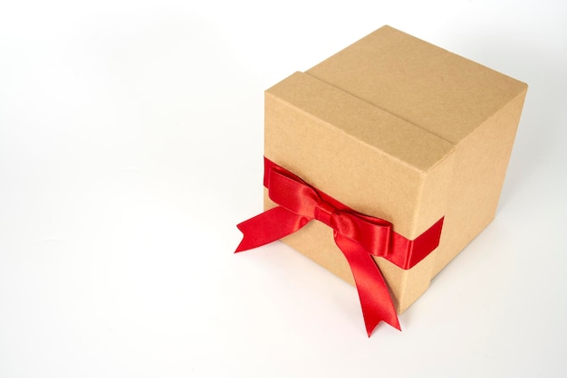 Scatola regalo di cartone marrone con un nastro rosso su sfondo bianco
