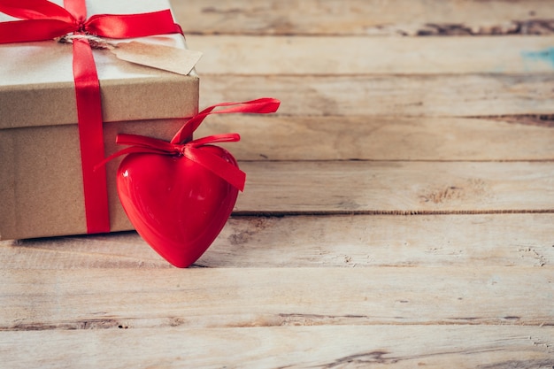 Scatola regalo e cuore rosso sul tavolo di legno con spazio
