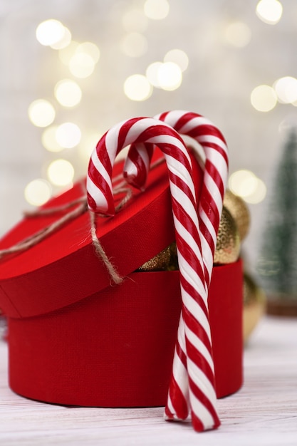 Scatola regalo rossa di Natale Decorazione con bastoncini di zucchero su bokeh