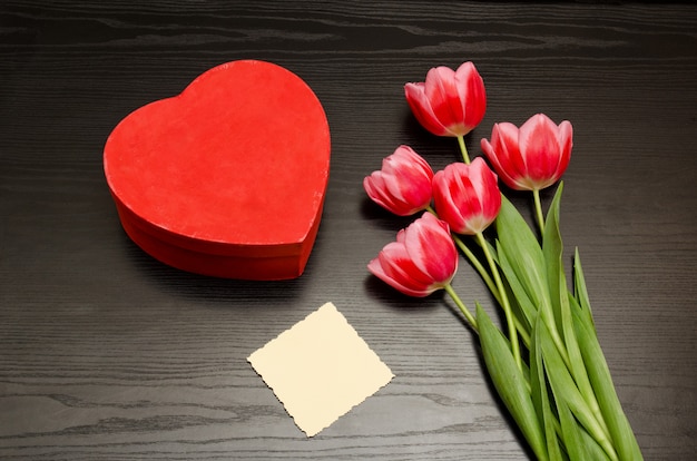 Scatola rossa a forma di cuore, cartoncino bianco e tulipani rosa