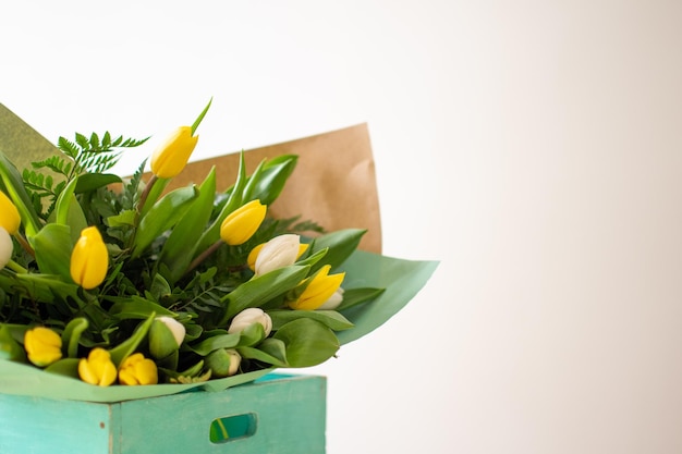 Scatola rustica turchese con bouquet di tulipani gialli e bianchi