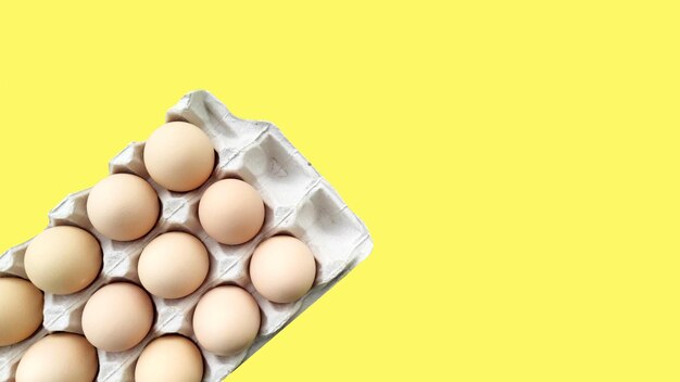 Scatola vassoio con uova chickenorganic isolate su sfondo giallo Il concetto di cibo sano farmin