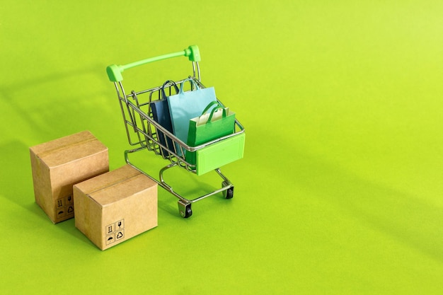 Scatole di cartone o scatole di carta nel carrello su sfondo verde Concetto di servizio di acquisto e consegna online