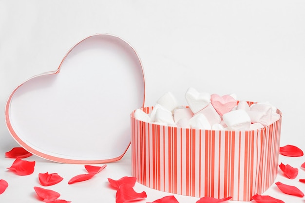 Scatole regalo a forma di cuore di San Valentino con cuori di marshmallow all'interno su sfondo bianco