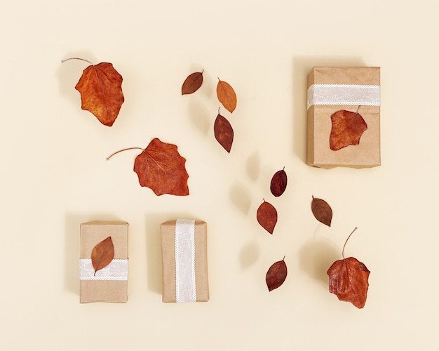 Scatole regalo autunnali fai da te in carta artigianale decorata con foglie secche rosse su beige