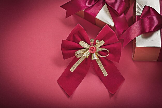 Scatole regalo avvolte con nodo di Natale su sfondo rosso concetto di vacanze