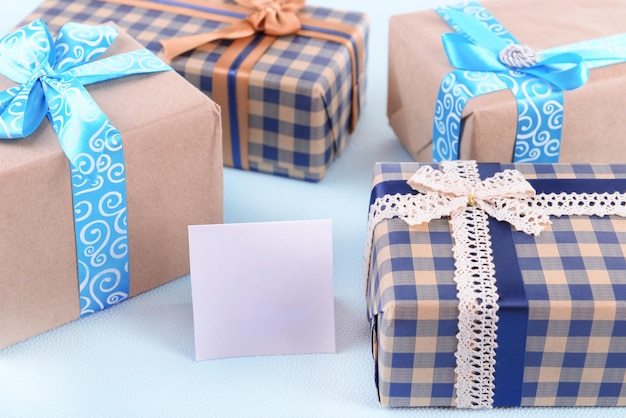 Scatole regalo con biglietto di auguri su sfondo azzurro irregolare