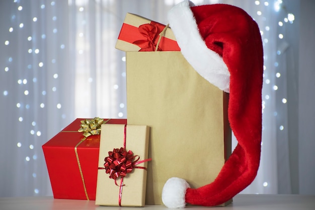 Scatole regalo con cappello di Babbo Natale sul sacchetto di carta con bokeh di luci di Natale