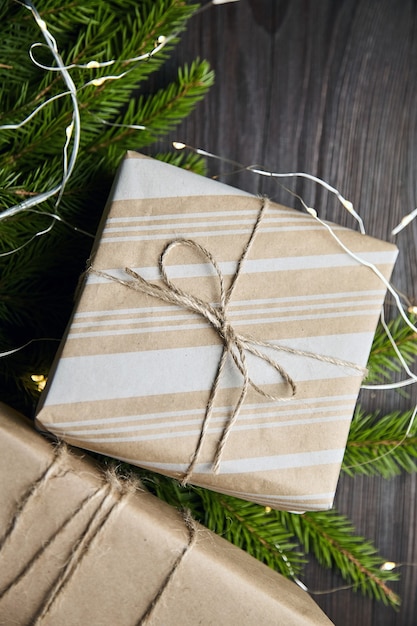 Scatole regalo con luce di Natale e rami di abete verde su fondo di legno marrone