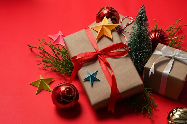 Scatole regalo con nastro rosso e decorazioni di ornamenti natalizi su sfondo rosso.