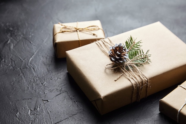 Scatole regalo con rami e coni verdi dell'albero di Natale su sfondo scuro