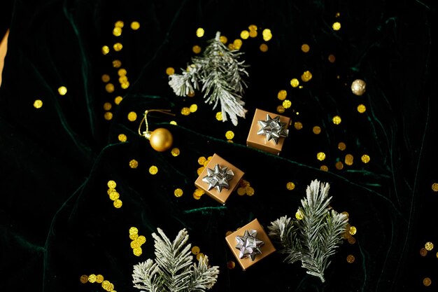 Scatole regalo d'oro con nastro d'argento su sfondo verde vellutato brillante con decorazioni natalizie Spazio di copia piatto laico Buon Natale