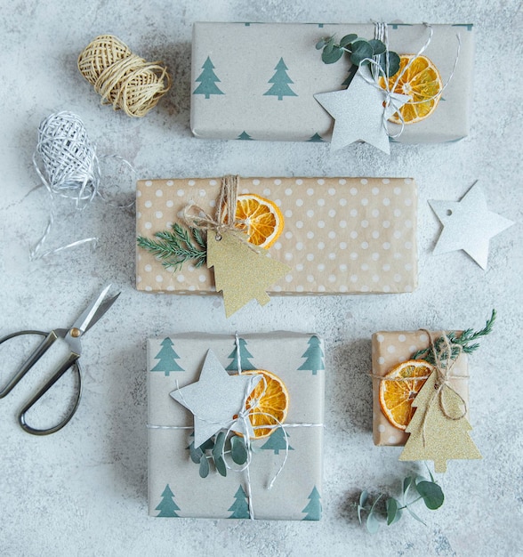Scatole regalo decorative natalizie fatte in casa avvolte in carta kraft marrone su uno sfondo di cemento grigio