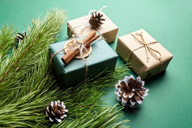 Scatole regalo di Natale e rami di pino con decorazioni su sfondo verde