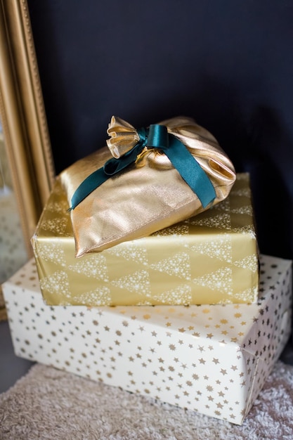 Scatole regalo di Natale in oro e bianco su uno sfondo di muro nero
