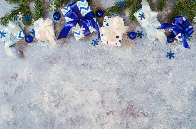 Scatole regalo e rami di abete con decorazioni in colore blu.
