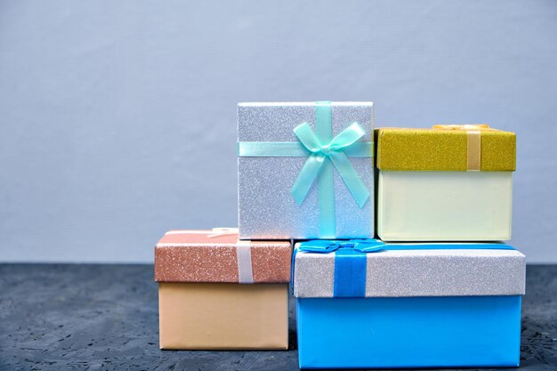 Scatole regalo multicolori con fiocchi di diversi colori su sfondo grigio