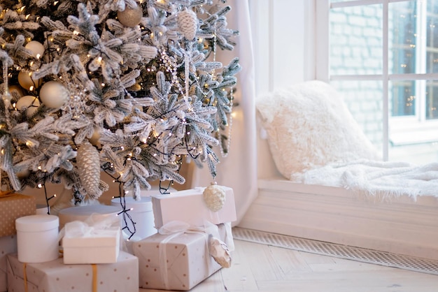 Scatole regalo presenti vicino all'albero di Capodanno decorato. Sfondo di Natale. Messa a fuoco selettiva morbida.