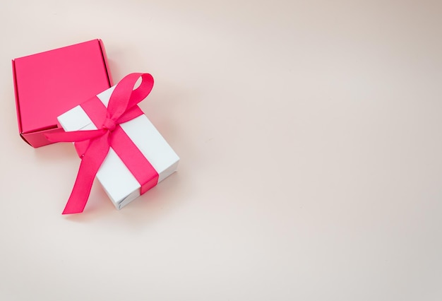 Scatole regalo rosa e bianche su sfondo beige con spazio per il testo Concetto di regali per la festa della mamma