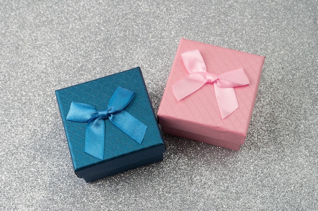 Scatole regalo rosa e blu con fiocco su sfondo scintillante.