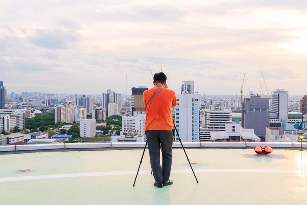 Scattare foto utilizzando un treppiede Fotografo che intende scattare foto sul grattacielo del cielo
