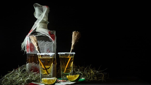 Scatti di tequila con decorazioni di halloween bicchieri di bottiglia bendati con facce spaventose e scope di streghe