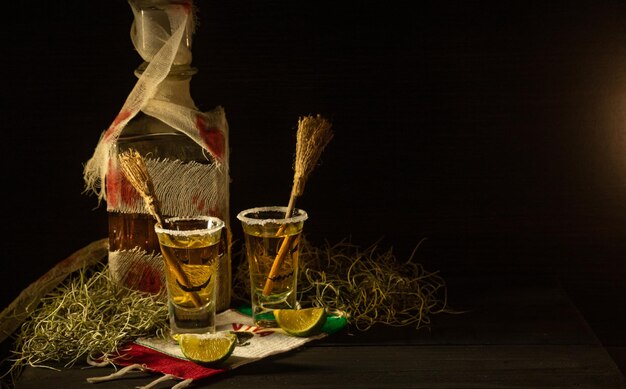 Scatti di tequila con decorazioni di halloween bicchieri di bottiglia bendati con facce spaventose e scope di streghe