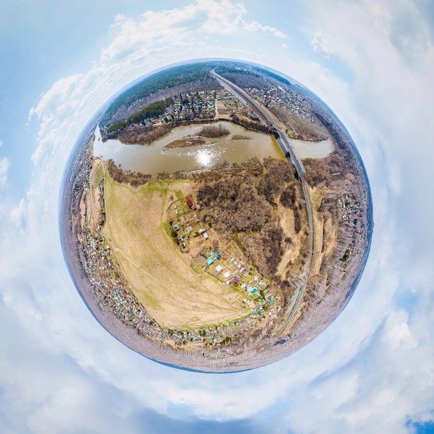 Scatto da drone in elicottero Fotografia aerea di un grande villaggio su un'area con piccole case una foresta verde e un grande campo in una calda giornata estiva soleggiata Città panoramica 360 ripresa dall'alto