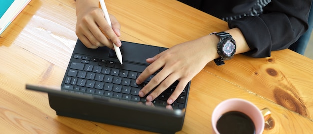 Scatto dall'alto della donna utilizzando la tavoletta digitale con stilo e tastiera