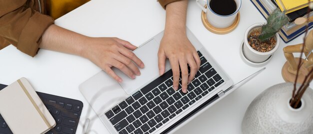 Scatto dall'alto di studente che digita sulla tastiera del laptop