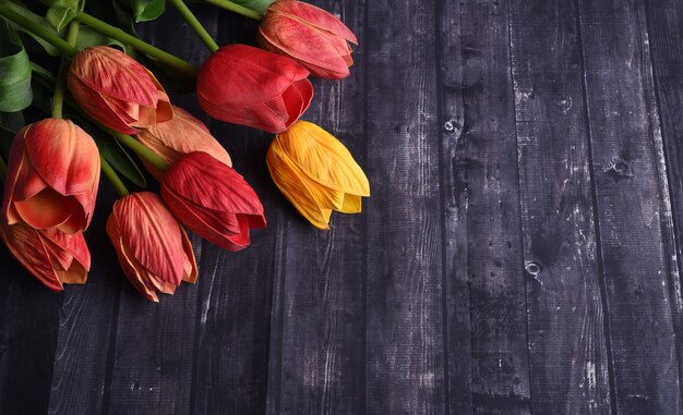 Scatto dall'alto un mazzo di tulipani arancioni e gialli su un tavolo di legno rustico