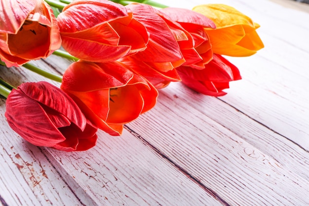 Scatto dall'alto un mazzo di tulipani arancioni e gialli su un tavolo in legno rustico. Stile piatto vista dall'alto. accettare il concetto di doni