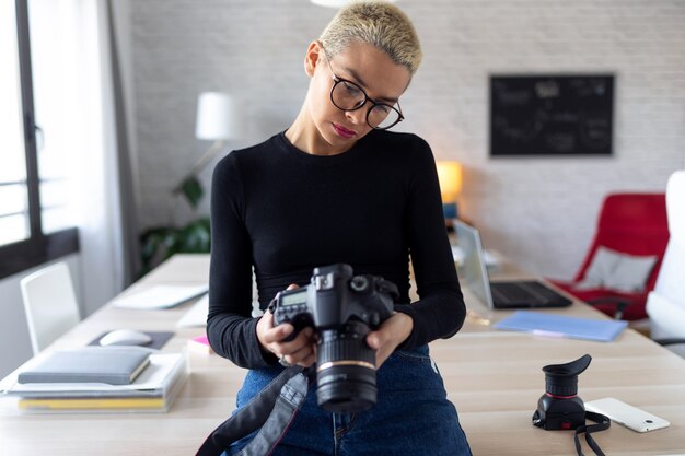 Scatto di una giovane imprenditrice moderna che rivede le sue ultime fotografie nella fotocamera mentre è seduta in ufficio.