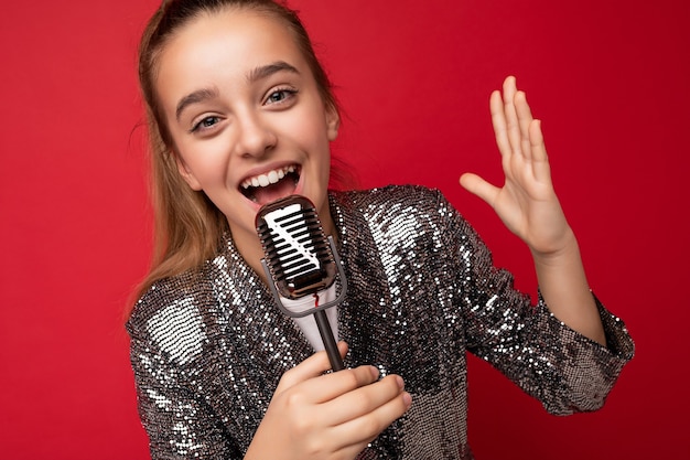 Scatto fotografico di una bambina bruna positiva e attraente che indossa un vestito brillante alla moda