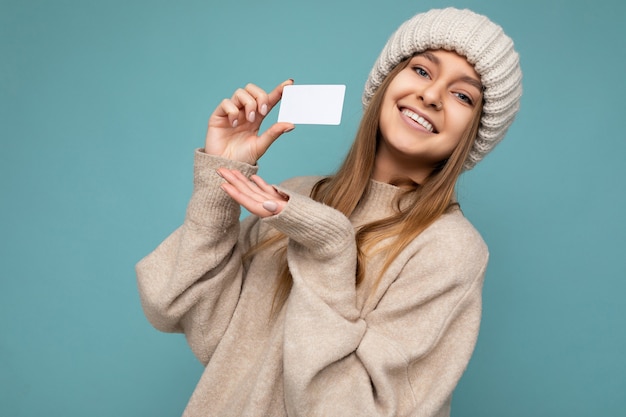 Scatto fotografico di una bellissima giovane donna bionda scura sorridente positiva sexy che indossa un maglione beige e