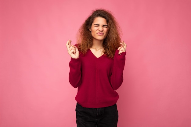 Scatto fotografico di una giovane bella donna bruna riccia con emozioni sincere che indossa una maglia rosa alla moda