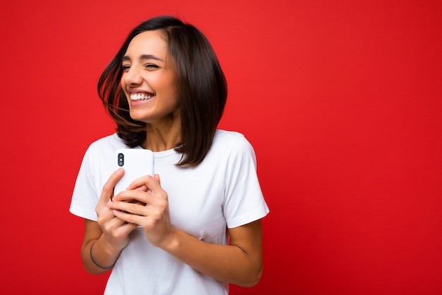 Scatto fotografico di una giovane donna bruna di bell'aspetto, positiva e sorridente, che indossa casual