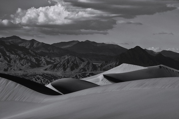 Scatto idilliaco di dune di sabbia e montagne nel deserto contro il cielo