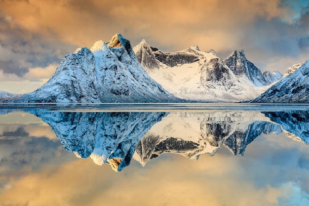 Scatto idilliaco di montagne innevate riflesso nel lago contro il cielo
